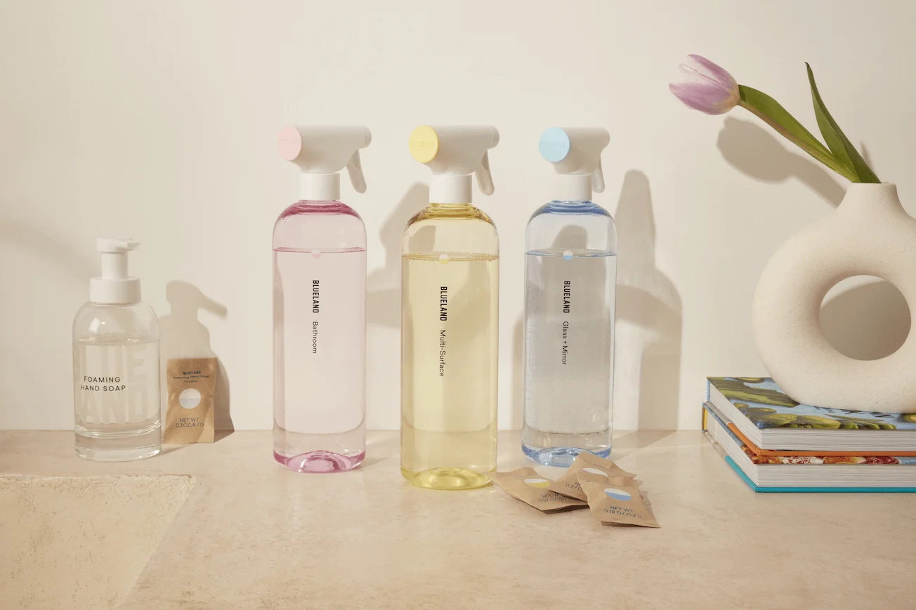 Bottle of Blueland eco-friendly cleaner sitting on a counter next to a flower and a stack of books